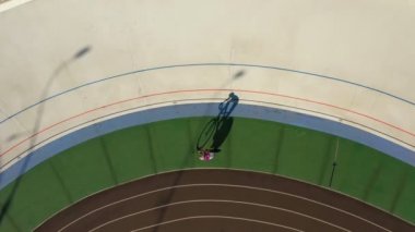bir döngü Velodrome parça üzerinde bisikletçi eğitim bir daire içinde sürmek. Havadan video görüntüleri. Üst görünüm uzun gölgeler. Spor teması