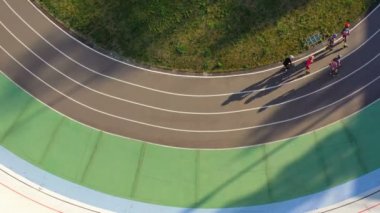 Profesyonel spor eğitim bisikletçi ve Roller patenciler bir daire içinde binmek. Video görüntüleri. Havadan görünüm uzun gölgeler akşam ışığı