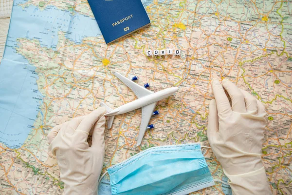 Covid. travel agency flights bans during quarantine. Tourism industry crisis restrictions theme. International virus pandemic lock down. Table top view map, plane, face mask, passport, hand in gloves