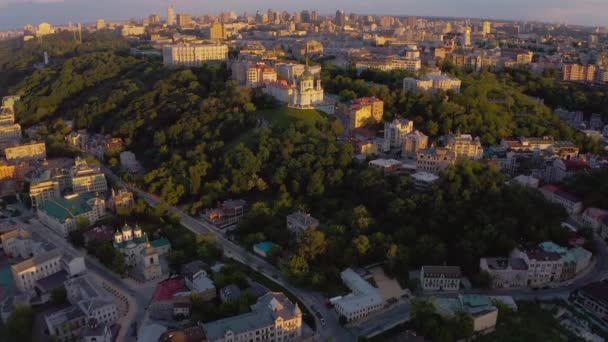 アンドリュイフスキー デセントと聖アンドリュー教会キエフ キエフ 東ヨーロッパのウクライナの首都 歴史的な丘の上に美しい夕日の光 上からの空中ドローンのパノラマビュー — ストック動画