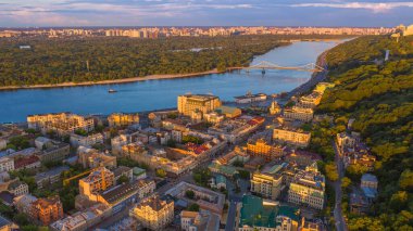 Kyiv (Kiev) Ukrayna 'nın Podol bölgesinin başkenti Sahaidachnoho Caddesi ve Dnipro nehrinin yukarıdan insansız hava aracı görüntüsü. Güneşin batışı güzel, sıcak bir ışık. Trukhaniv Adası 'na yaya köprüsü.  