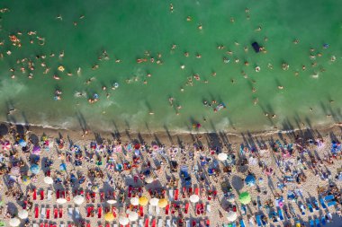 Deniz kenarında kalabalık bir tatil köyü. Plaj yaz havasında eğleniyorum. Yukarıdan gelen orijinal hava aracı sanatsal kompozisyonu. Üst görünüm olağandışı bakış. Odessa Ukrayna Karadeniz tatil beldesi. 