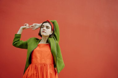 Kırmızı ve yeşil. Güzel, rahat, genç bir kadın şık bir ceket ve saç bandıyla şık bir moda arıyor. Sanatsal trendler. Nesil Zoomerlar. parlak doymuş neşeli renk karışımı