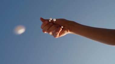 El kameranın üstüne inci boncuklar düşürür. Rahatlatıcı, saf, romantik, yaratıcı Ağır çekim video görüntüleri. Arka planda mavi yaz gökyüzü. Ev yapımı kız dekorasyonu. Güzel hobi zamanı.