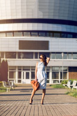 Şehirde yürüyen, elbise giymiş bir iş kadını..