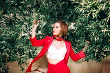 Kırmızı elbiseli bir kadın ve yeşil yapraklı bir başörtüsü..