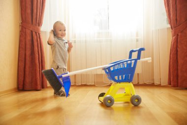 Adorable cute baby boy helper mopping room floor
