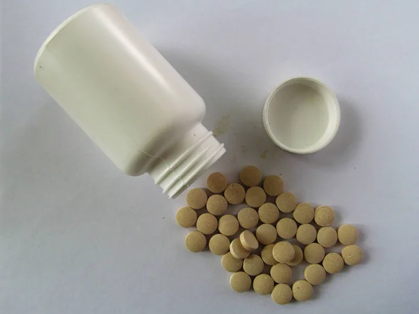Fehér jar, szétszórt tablettával a világos háttér előtt — Stock Fotó