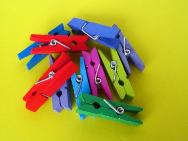 Elbiselerini ipe asmak için clipper. Sarı arka plan üzerinde çok renkli ahşap dekoratif klip.