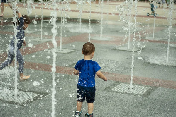 İnsanlar çeşmeler ile yaz aylarında yer arasında yürüyüş ve çıplak ayak sıçramaları yapma çıplak ayakile suda çalışan zevk. Sıcak güneş ışığı degradeli siyah beyaz fotoğraf