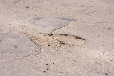 Kötü yollar. Asfalt delik, araba ile hareket riski, kötü asfalt, tehlikeli yol, asfalt çukurlar, çukur güvensiz delik yol konsepti. Çukurdaki yol işaretleri.