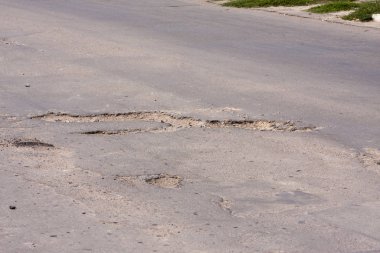 Kötü yollar. Asfalt delik, araba ile hareket riski, kötü asfalt, tehlikeli yol, asfalt çukurlar, çukur güvensiz delik yol konsepti. Çukurdaki yol işaretleri.