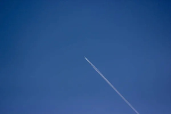 Un aereo nel cielo, traccia da un aereo in un cielo blu — Foto Stock