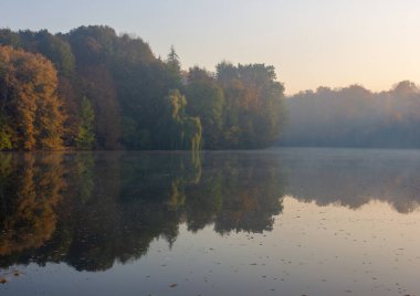 Sonbahar yapraklarının göl yansımaları. Renkli sonbahar yaprakları sakin sulara yansıyor. Sonbahar manzarası.