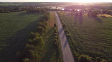 Akşam manzarası, dumanın gittiği gölete giden yolda uçmak. Akşam güneşinin alçak parıltısından yükselen gölgeler.
