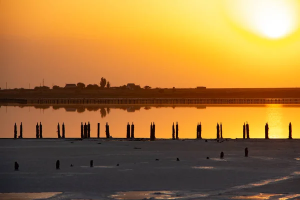 Orange light from sunset over salt lake with wooden colic