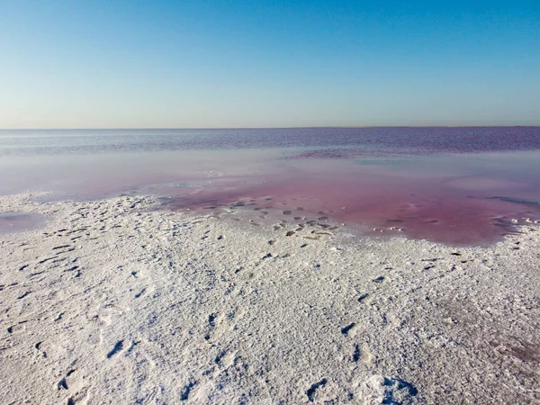 Landscape on a pink lake and pink salt that covers the entire shore of the lake.