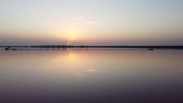 Quadcopterflug über einen rosafarbenen See am Morgen, Sonnenaufgang und Reflexion des orangen Lichts im Wasser. Möwen wachten auf und flogen herum. — Stockvideo