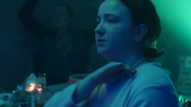 여자는 vape 흡연 파티에서 테이블에 앉아 있다. 그들은 랩, 힙합에 춤. — 비디오