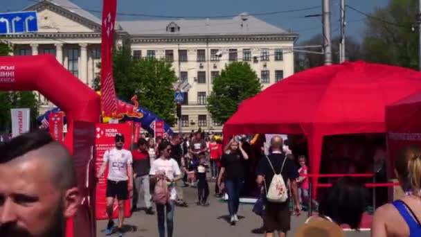 Ludzie, uczestnicy i Organizatorzy Maratonu w Zaporizhzhia, Ukraina, Kwiecień 27, 2019. Trasa dla biegaczy, organizator "New mail" straganów. — Wideo stockowe