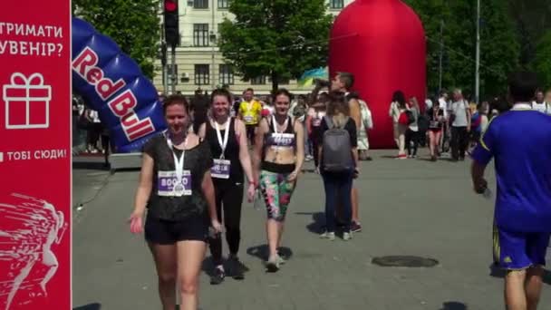 Joyeux, joyeux et mécontents participants du marathon, jeunes, belles, filles en T-shirts et leggings, vêtements de sport, après avoir couru, dans la peinture Holi, approcher le public, partager leurs impressions — Video