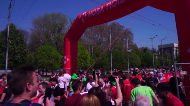 Diferiți oameni, copii în culori de holi, recurg la finalizarea maratonului. La finiș întâlniți participanți, spectatori, fani, poștă nouă. Felicitări tuturor, distribuiți apă, medalii — Videoclip de stoc