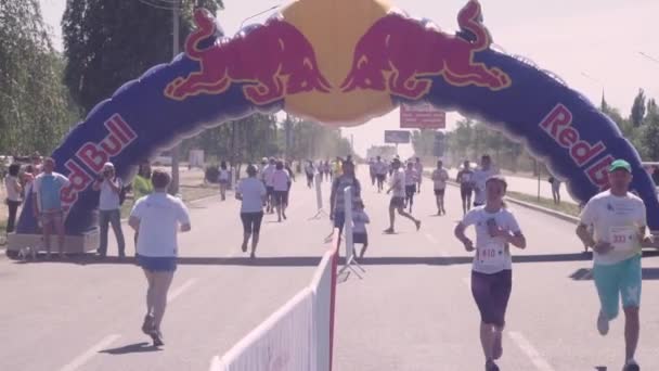 Di jalan, jalan aspal berjalan dalam dua arah, dipisahkan oleh pelari maraton pagar, dengan cat holi, di festival Bright Run 2018. Pria dan wanita dalam kaos putih dan nomor, dalam topi — Stok Video