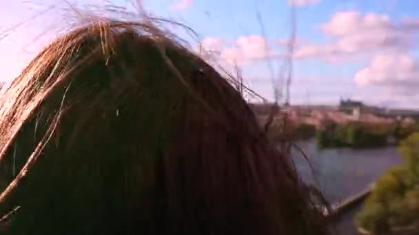 The wind blows the brown hair of a girl who watches with binoculars to the entire old city of Prague, on the roof of a dancing house. At the end of the camera comes close to the lens. — Stock Video