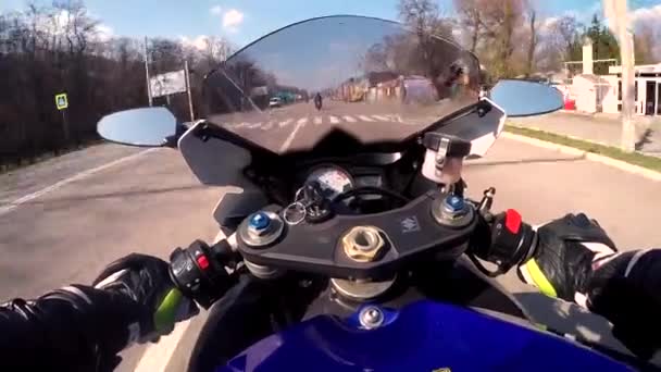 DNEPR, UKRAINE - APRIL 14, 2019: A motorcyclist on a blue sports bike rides through the town of asphalt-grained, bad, not level, with a hill and trampolines going around the road. Motorcycle throws up — Stock Video