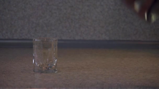 桌子上有一个空酒杯，一只手从透明瓶子里倒伏特加，从框架中取出玻璃杯，喝，把一个空玻璃杯和瓶子放回桌面. — 图库视频影像