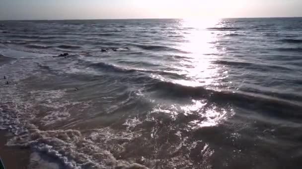 La mer de gris, en été, par temps venteux, force les vagues, la mousse se forme sur le rivage, et surfe. Chemin solaire, horizon, ciel bleu, plage de sable, sans nuages et nuages. Mouvement lent . — Video