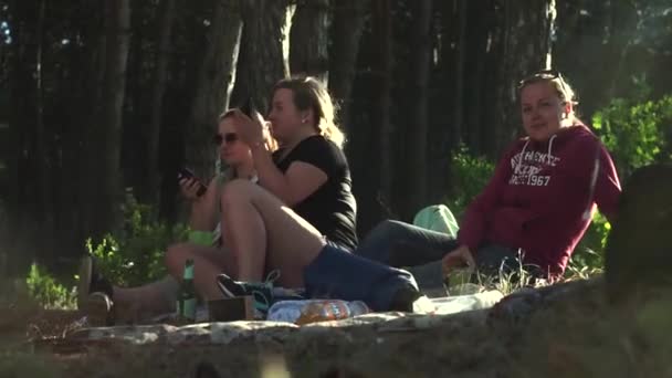 Trois belles jeunes filles, assises sur le couvre-lit, par terre en jeans, sweat-shirt, short, costume, baskets, baskets, sandales, lunettes de soleil, fumer une cigarette électronique pendant des heures et boire — Video