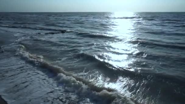 Blauw, groen, turquoise zee, wind, golven, zon, zwarte stenen, zonnige pad, zomer, warm, winderig, dag, schuim, surfen, tegen de blauwe lucht. Slow Motion. — Stockvideo