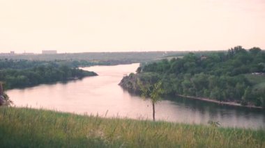 Güçlü, ciddi adam yürür, güzel yeşil ağaçlar, çimen, nehir, evler, ada, doğa, kayalar düşünüyor