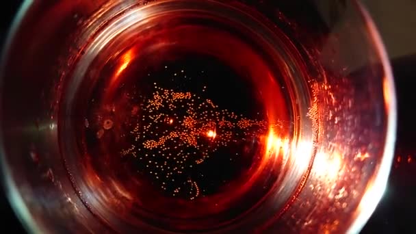 Nahaufnahme, aufsteigende Blasen im beleuchteten Glas darüber mit rotem Champagner — Stockvideo