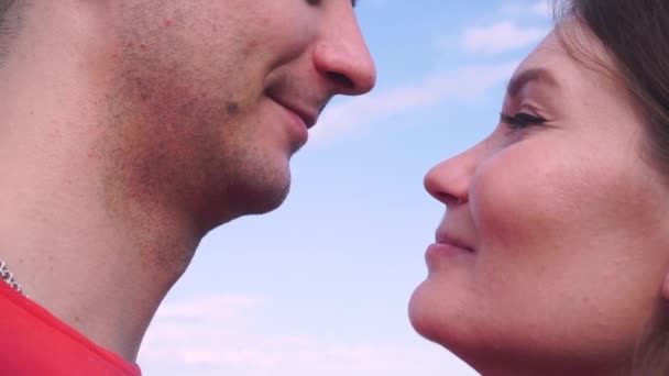 Крупным планом, мальчик и девочка нежно целуются на фоне неба — стоковое видео