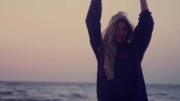 Das schöne Mädchen mit den langen Haaren dreht sich um sich selbst, freut sich, lacht. Meer, Wellen, Wind im Hintergrund — Stockvideo