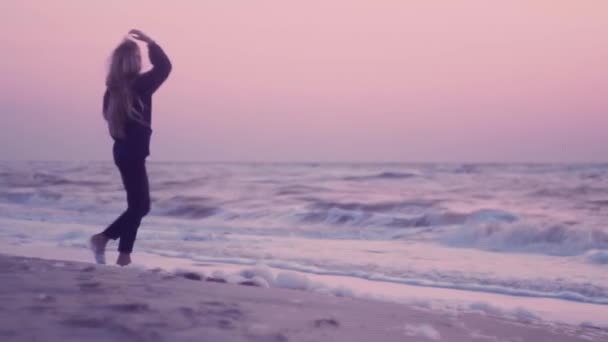 일출에 해변의 젖은 모래에 걷는 아름다운 소녀 — 비디오