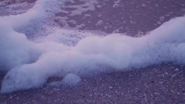 Espuma de las olas que se balancean en el viento sobre la arena mojada del mar — Vídeo de stock