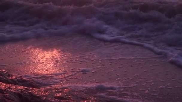Wellen, Schaum, Brandung, auf dem nassen Sand, dem dunklen Meer, vor dem Hintergrund eines orangen Sonnenuntergangs — Stockvideo