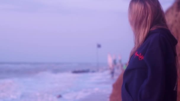 Menina elegante olha para o mar frio azul, com vento, ondas e espuma — Vídeo de Stock