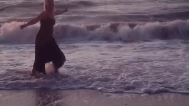 Kobieta w czarnej sukni biegnie do jej boku rozprzestrzeniania. ramiona do objęcia, na morzu, duże fale — Wideo stockowe
