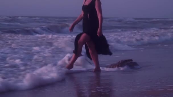 Μια γυναίκα περπατά σε ισχυρά κύματα, με αφρό, ακτή, θάλασσα, άμμο, το καλοκαίρι, το βράδυ — Αρχείο Βίντεο