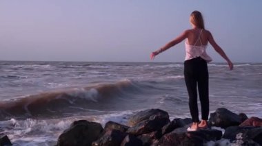 Bir t-shirt komik sarışın denizde kayalar üzerinde duruyor, o dalgalar püskürtülür alır