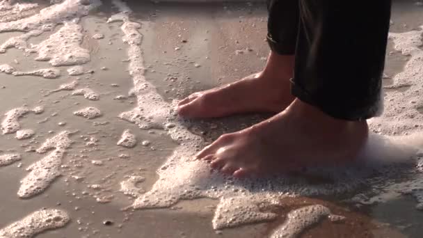 젖은 모래에 검은 청바지에 여자 다리 는 거품과 파도 를 세차 — 비디오