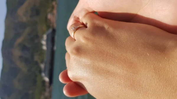 Mão da esposa com um anel de casamento, em cima da mão do marido, no fundo de um navio de cruzeiro, montanhas — Fotografia de Stock
