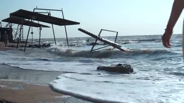 Dívka kráčí podél příboje vln moře, pláž kolem starých pavilonů — Stock video