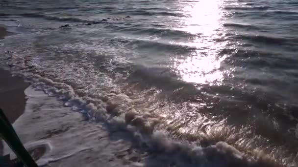 De zee van grijs, in de zomer, bij winderig weer, dwingt golven, schuim wordt gevormd op de kust, en surfen. Zonnepad, horizon, zandstrand. Langzame beweging. — Stockvideo