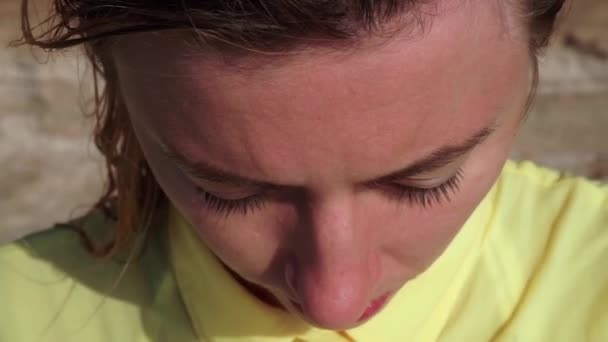Parlak güneşin altında genç ve üzgün bir kızın alnına yakın çekim — Stok video