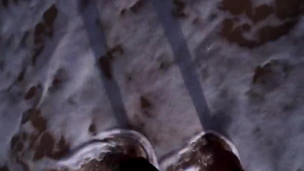 Nogi męskie stoją w brudnym morzu, w szortach na wietrze, wokół fali — Wideo stockowe